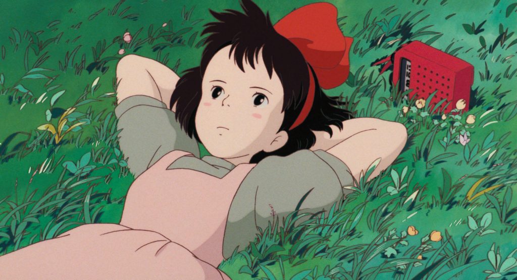 Kiki resting in grass beside her red radio