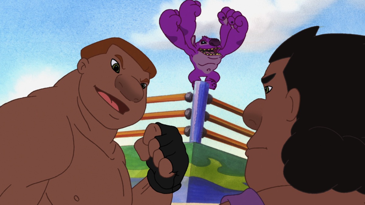 Official episode still of Kixx celebrating inside a kickboxing ring behind two fighters