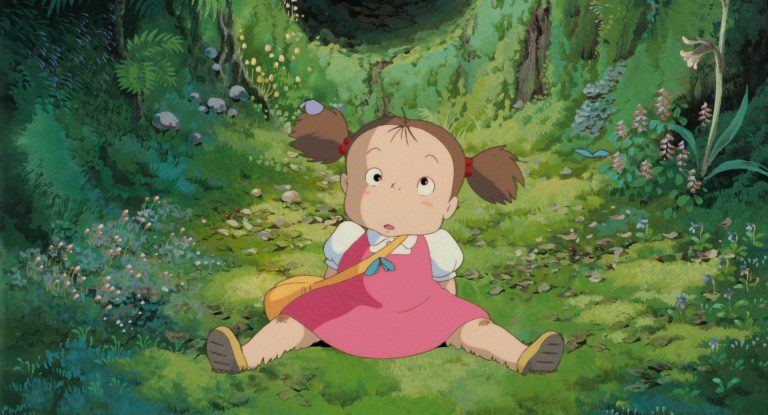 Mei sitting alone on a forest path surrounded by summer plants