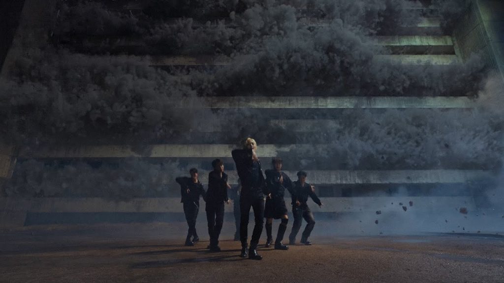 ONF performing as debris and storm clouds fill the Bye My Monster music video.