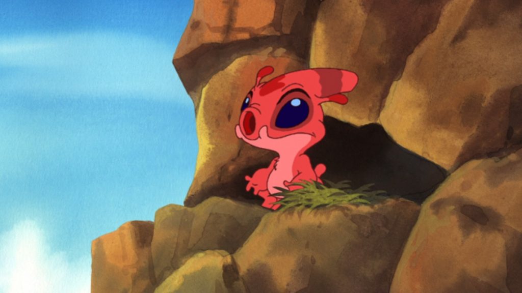 Official episode still of the red experiment Splodyhead watching from a rocky island ledge