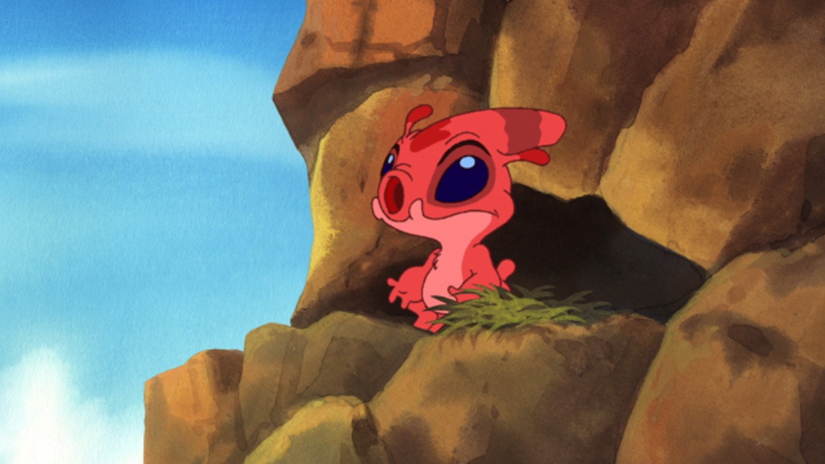 Official episode still of the red experiment Splodyhead watching from a rocky island ledge