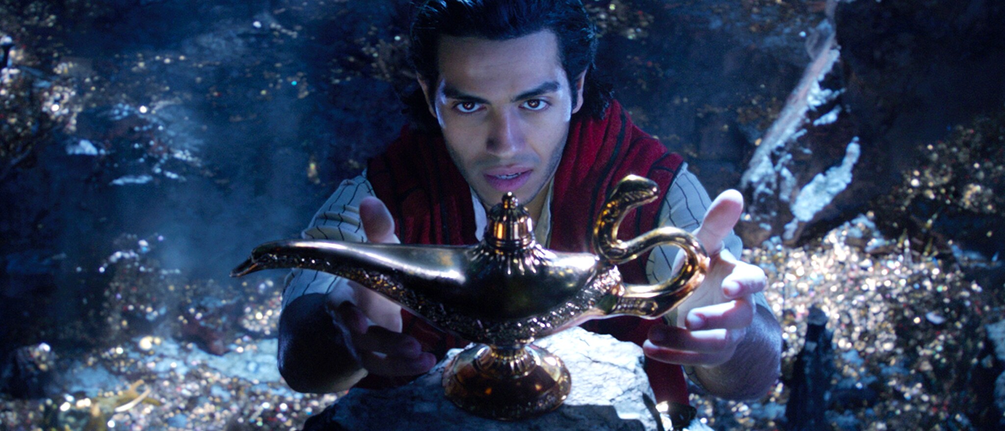 Mena Massoud as Aladdin reaches toward the magic lamp in an official Disney still