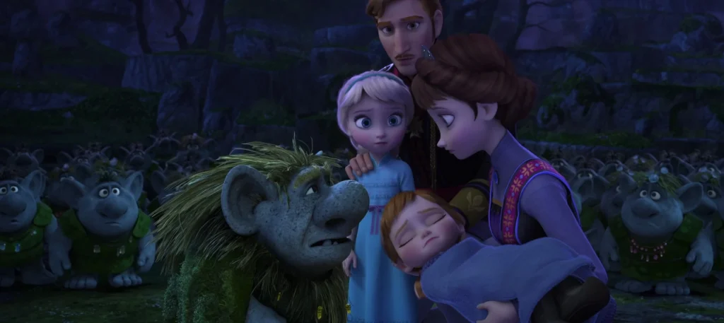 Grand Pabbie helps young Anna while the Arendelle royal family watches in an official Frozen film still