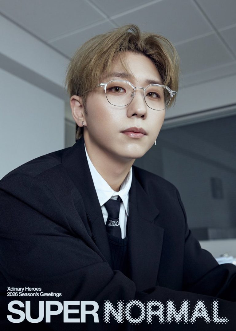 Gunil of Xdinary Heroes seated in a black suit for the official 2026 SUPER NORMAL season greeting